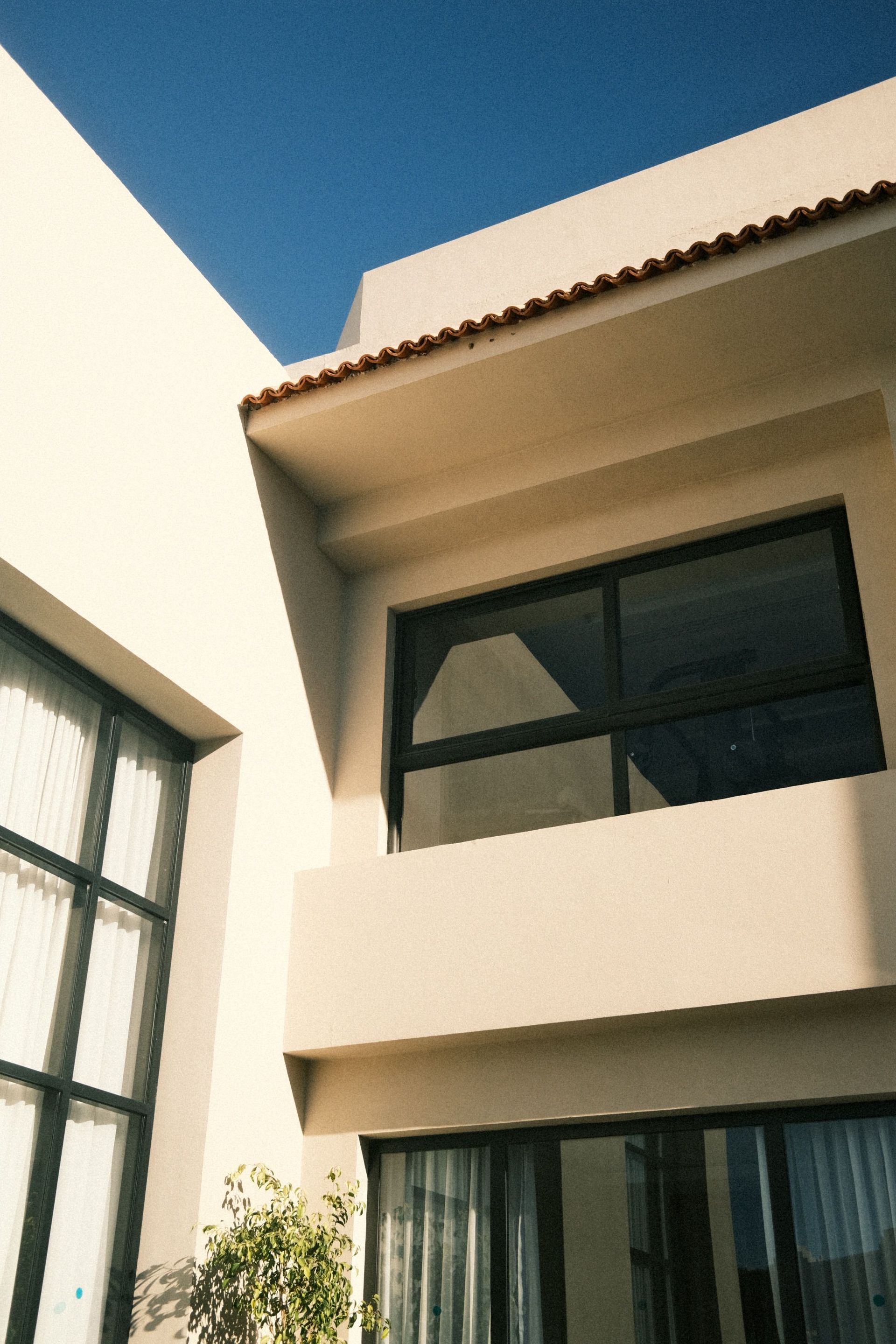 Elegant modern house exterior with large windows under clear blue sky.