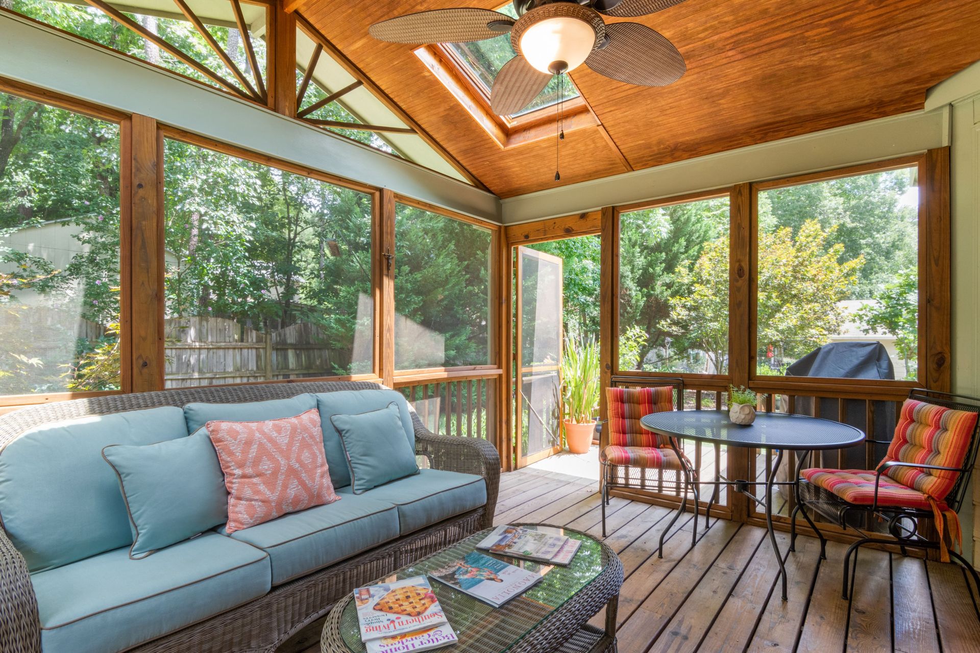 Inviting indoor porch with skylight, wicker sofa, and vibrant decor, perfect for relaxation.